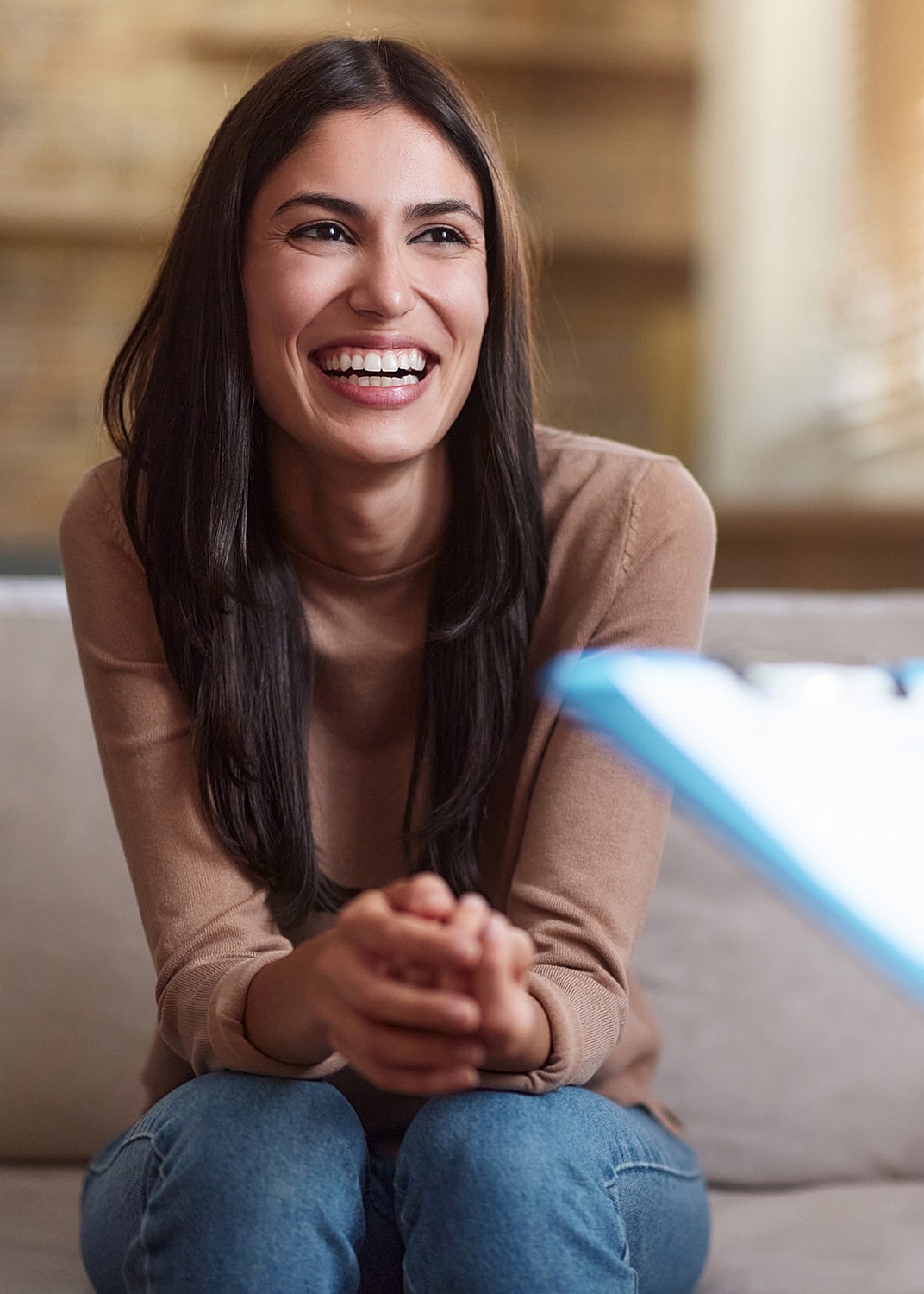 Smiling woman sitting on a sofa, relaxed atmosphere.
